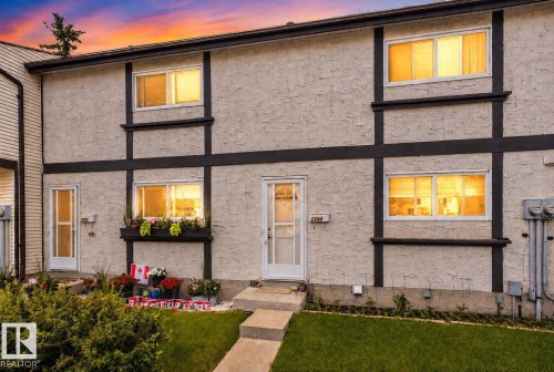 Stucco exterior featuring dark trim accents, a concrete walkway, and an established lawn - 1344 Lakewood Road West Nw, Edmonton, AB - Outdoor