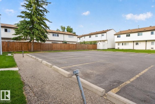 Paved parking area featuring designated spaces with yellow striping and concrete parking blocks - 1344 Lakewood Road West Nw, Edmonton, AB - Outdoor
