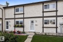 Stucco exterior with decorative dark trim, white frame windows, an individual entry door, a concrete pathway, and a grassy front yard - 1344 Lakewood Road West Nw, Edmonton, AB  - Outdoor 