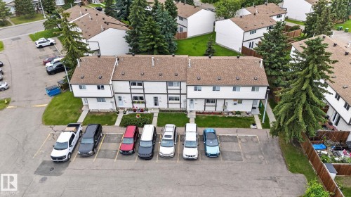 Townhome exterior featuring white siding, brown shingle roofing, and dark trim accents - 1344 Lakewood Road West Nw, Edmonton, AB - Outdoor