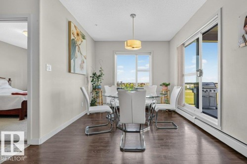 Bright dining area with floor-to-ceiling glass doors and windows flooding the space with natural light - #423 320 Ambleside Li Sw, Edmonton, AB - Indoor Photo Showing Dining Room