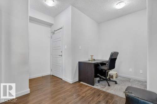 Wood-finish flooring, white paneled interior door, and overhead lighting fixtures - #423 320 Ambleside Li Sw, Edmonton, AB - Indoor Photo Showing Other Room