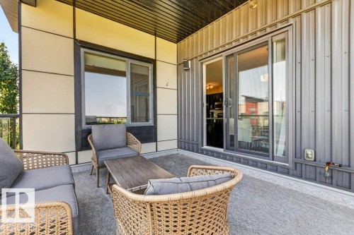 Covered outdoor patio with a textured concrete surface, modern panel siding, and a sliding glass door - #423 320 Ambleside Li Sw, Edmonton, AB - Outdoor With Deck Patio Veranda With Exterior