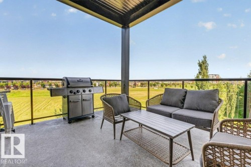 Expansive outdoor concrete patio with glass railing and durable overhead pergola - #423 320 Ambleside Li Sw, Edmonton, AB - Outdoor With Exterior