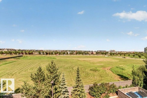 Expansive green space and a distant cityscape under a clear sky - #423 320 Ambleside Li Sw, Edmonton, AB - Outdoor With View