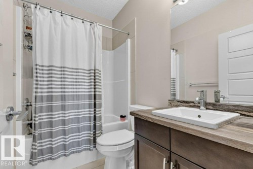 Vanity with wood-finish countertop, undermount sink, chrome faucet, and integrated storage - #423 320 Ambleside Li Sw, Edmonton, AB - Indoor Photo Showing Bathroom