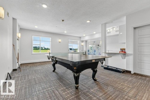 Spacious room featuring multiple windows, recessed ceiling lighting, wall sconces, and patterned carpet flooring - #423 320 Ambleside Li Sw, Edmonton, AB - Indoor Photo Showing Other Room