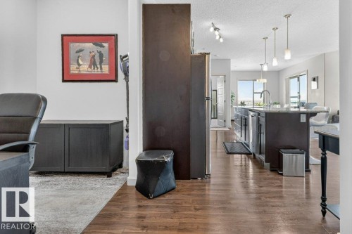 Wood-finish flooring throughout, kitchen island with built-in stainless steel appliances, pendant lighting, track lighting, and sliding glass doors - #423 320 Ambleside Li Sw, Edmonton, AB - Indoor