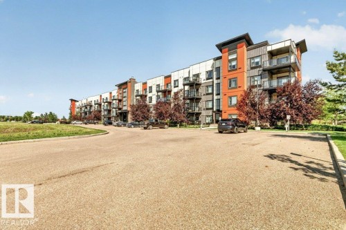 Contemporary multi-story building with balconies, exterior parking, landscaped grounds, and mature trees - #423 320 Ambleside Li Sw, Edmonton, AB - Outdoor With Balcony