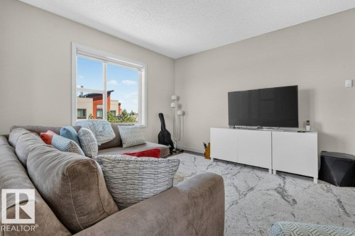 Expansive window, neutral wall paint, textured ceiling, and wood-finish flooring - #423 320 Ambleside Li Sw, Edmonton, AB - Indoor