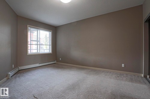 Neutral wall finishes, light-colored carpeting, and a single window with horizontal blinds - #209 304 Ambleside Link Li Sw Sw, Edmonton, AB - Indoor Photo Showing Other Room