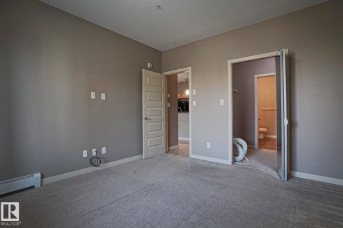 Carpeted flooring with neutral wall tones and a baseboard heater - #209 304 Ambleside Link Li Sw Sw, Edmonton, AB - Indoor