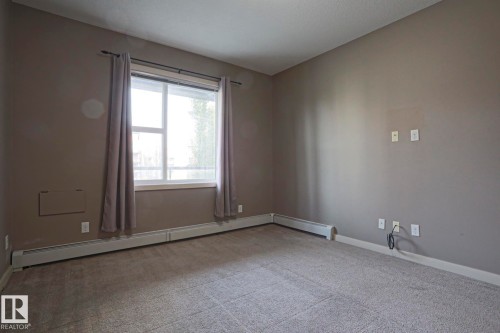 Carpeted flooring, neutral wall paint, and a large window with white trim - #209 304 Ambleside Link Li Sw Sw, Edmonton, AB - Indoor Photo Showing Other Room