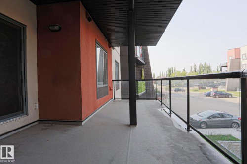 Private balcony with a concrete floor, glass and metal railings, and a soffit ceiling - #209 304 Ambleside Link Li Sw Sw, Edmonton, AB - Outdoor With Balcony With Exterior
