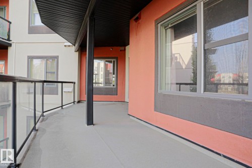 Spacious balcony featuring glass panel railings, a solid overhead covering, and a neutral-toned floor finish - #209 304 Ambleside Link Li Sw Sw, Edmonton, AB - Outdoor With Balcony With Exterior