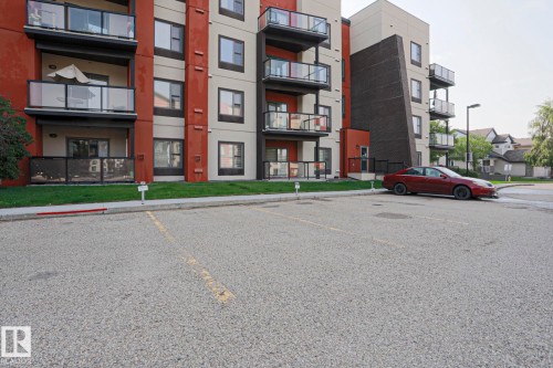 Multi-story residential building with private balconies featuring glass railings and a dedicated parking area - #209 304 Ambleside Link Li Sw Sw, Edmonton, AB - Outdoor With Balcony With Facade