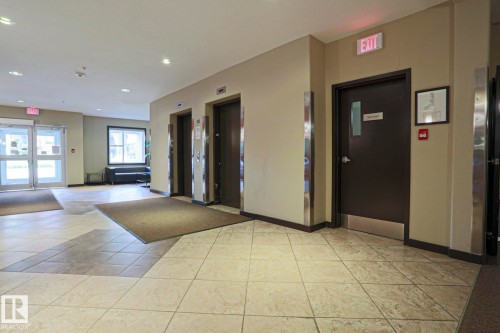 Tile flooring with geometric patterns, multiple elevators with stainless steel accents, and glass-paneled entry doors - #209 304 Ambleside Link Li Sw Sw, Edmonton, AB - Indoor Photo Showing Other Room
