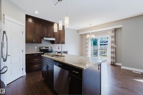 Kitchen island with a light-toned countertop, stainless steel dishwasher, and under-mount sink - 15839 10 Avenue Sw, Edmonton, AB - Indoor Photo Showing Kitchen With Stainless Steel Kitchen With Double Sink