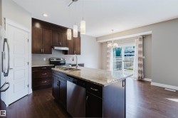 Kitchen island with a light-toned countertop, stainless steel dishwasher, and under-mount sink - 