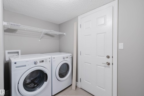 Laundry area with a wire shelf, light gray walls, and a paneled door - 15839 10 Avenue Sw, Edmonton, AB - Indoor Photo Showing Laundry Room