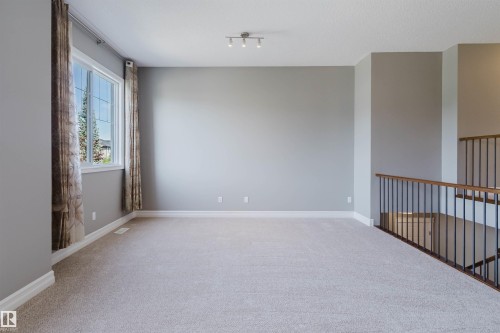 Spacious room with light-toned carpeting and neutral wall tones - 15839 10 Avenue Sw, Edmonton, AB - Indoor Photo Showing Other Room