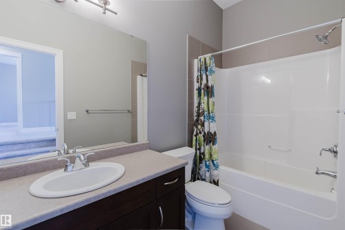 Single vanity with an integrated oval sink, chrome faucet, and wood-finish cabinetry - 15839 10 Avenue Sw, Edmonton, AB - Indoor Photo Showing Bathroom