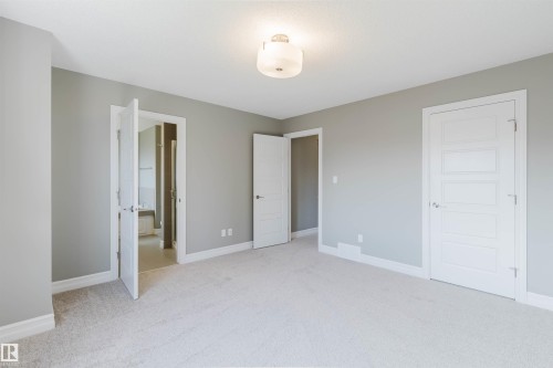 Neutral painted walls, light-colored carpet, white trim, white paneled doors, and an overhead flush mount light fixture - 15839 10 Avenue Sw, Edmonton, AB - Indoor
