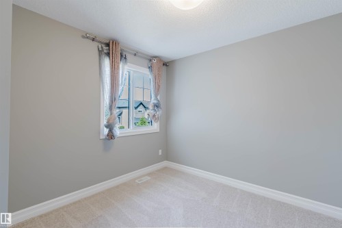 Neutral wall paint, carpet flooring, window with white trim, and ceiling light fixture - 15839 10 Avenue Sw, Edmonton, AB - Indoor Photo Showing Other Room