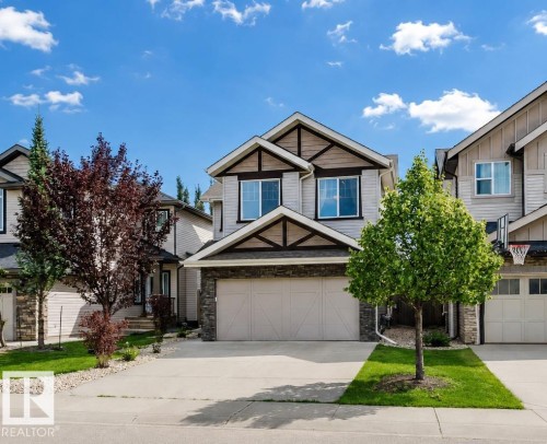 Two-story residence featuring light-colored siding, a prominent two-car garage, and stone facade accents - 15839 10 Avenue Sw, Edmonton, AB - Outdoor With Facade