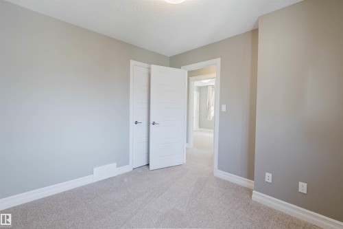 Neutral wall color, wall-to-wall carpeting, white trim, white interior doors, and overhead lighting - 15839 10 Avenue Sw, Edmonton, AB - Indoor Photo Showing Other Room