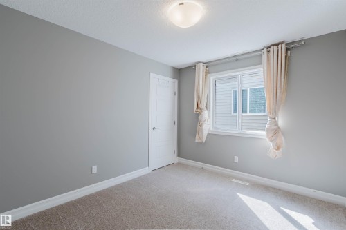Carpeted flooring, a window with horizontal blinds, a flush mount ceiling light, and a white paneled door - 15839 10 Avenue Sw, Edmonton, AB - Indoor Photo Showing Other Room