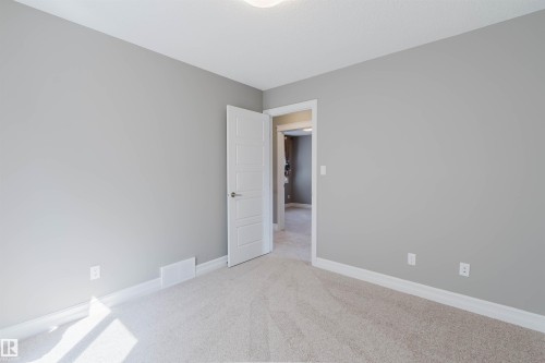 Neutral-toned wall finish, plush carpet flooring, white trim, and a contemporary panel door - 15839 10 Avenue Sw, Edmonton, AB - Indoor Photo Showing Other Room