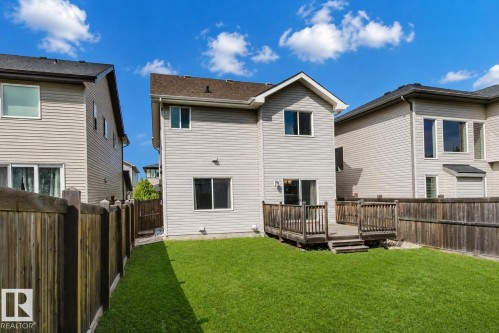 Expansive green lawn, elevated wood deck, sliding glass door access, and wood privacy fencing - 15839 10 Avenue Sw, Edmonton, AB - Outdoor With Exterior