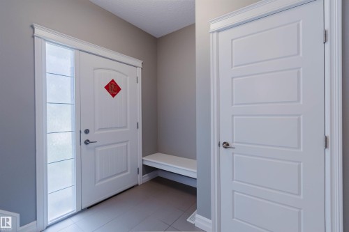 Entryway featuring a paneled door with frosted sidelight, white trim, and light gray wall paint - 15839 10 Avenue Sw, Edmonton, AB - Indoor Photo Showing Other Room