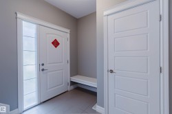 Entryway featuring a paneled door with frosted sidelight, white trim, and light gray wall paint - 