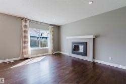 Wood-finish flooring, recessed lighting, and a modern fireplace with a tiled surround - 