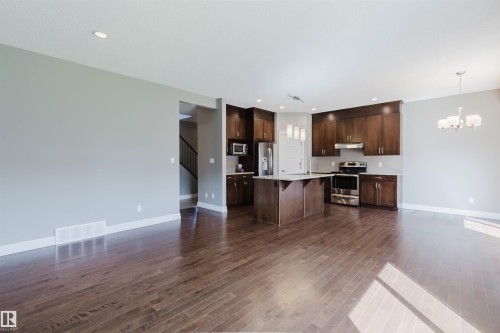Spacious open-concept living area with wood-finish flooring, recessed lighting, and a modern kitchen - 15839 10 Avenue Sw, Edmonton, AB - Indoor Photo Showing Kitchen