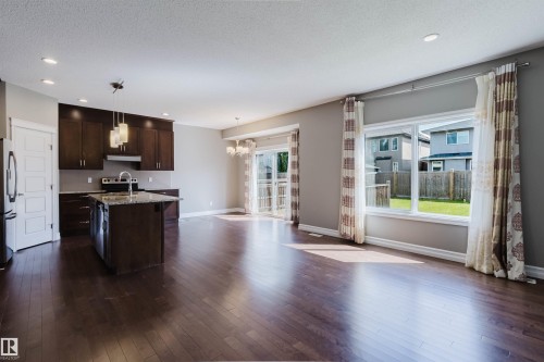Open-concept living area featuring rich wood-finish flooring, recessed lighting, and a kitchen island with stone countertops - 15839 10 Avenue Sw, Edmonton, AB - Indoor Photo Showing Other Room