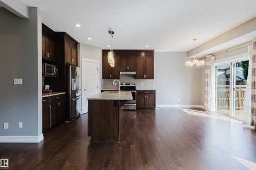 Open-concept living space with dark wood-finish flooring, recessed lighting, and a kitchen island with a stone countertop - 15839 10 Avenue Sw, Edmonton, AB - Indoor Photo Showing Kitchen