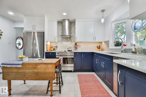Contemporary kitchen featuring two-tone cabinetry, stainless steel appliances, a tiled backsplash, and white countertops - 8932 187 Street Nw, Edmonton, AB - Indoor Photo Showing Kitchen With Double Sink