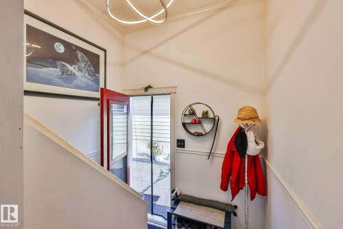 Red entry door with glass paneling, crown molding, and a modern ceiling light fixture - 8932 187 Street Nw, Edmonton, AB - Indoor Photo Showing Other Room
