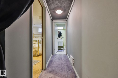 Hallway with purple carpet flooring, white baseboards, and a textured ceiling with a flush-mount light fixture - 8932 187 Street Nw, Edmonton, AB - Indoor Photo Showing Other Room