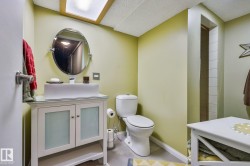 Vanity with opaque glass-front cabinetry, vessel sink, and an oval mirror - 