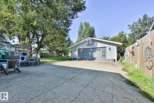 Detached garage with a grey sectional door, concrete driveway, and a wood privacy fence - 8932 187 Street Nw, Edmonton, AB - Outdoor