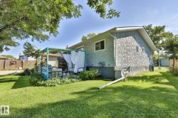 Expansive lawn area with mature trees, a stucco exterior, and a dedicated patio space featuring a pergola - 