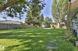 Expansive lawn area, mature trees, wood fence, and a stone pathway - 