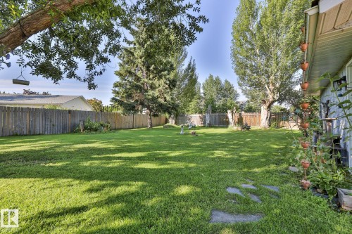 Expansive lawn area, mature trees, wood fence, and a stone pathway - 8932 187 Street Nw, Edmonton, AB - Outdoor With Backyard