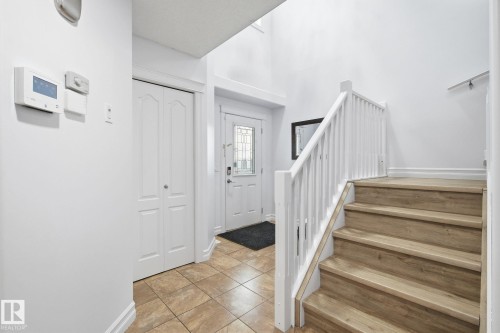 Foyer featuring tile flooring, a staircase with wood-finish treads and white risers, and a white balustrade - 3016 24 Ave Nw, Edmonton, AB - Indoor Photo Showing Other Room