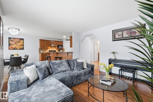 Hardwood flooring, arched doorway, recessed lighting, white walls, and a kitchen with wood-finish cabinetry - 3016 24 Ave Nw, Edmonton, AB - Indoor Photo Showing Living Room