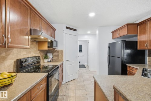 Full kitchen featuring wood cabinetry, stone-finish countertops, and a tiled backsplash - 3016 24 Ave Nw, Edmonton, AB - Indoor Photo Showing Kitchen With Double Sink